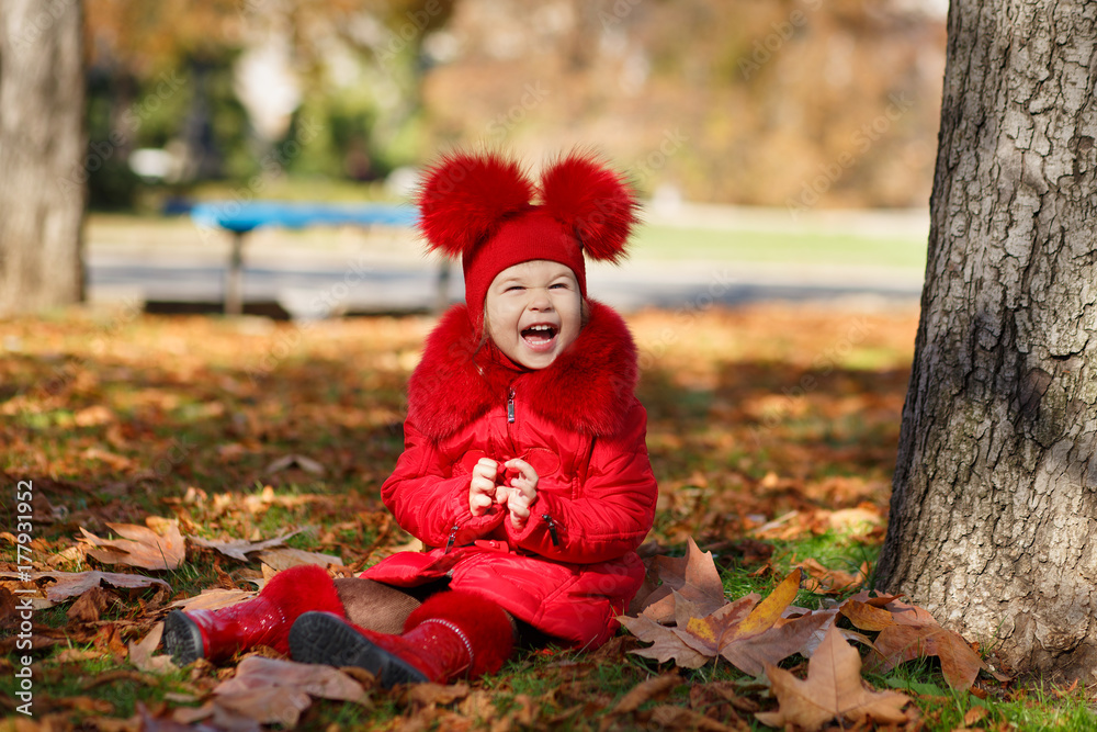 Dolly pin-up toothsome young girl wearing red blushful winter jacket and warm hat with boots fashion stylish clothes posing in autumn spring park weekend happyly smiling sitting on pathway track. Dolly pin-up toothsome young girl wearing red blushful winter jacket and warm hat with boots fashion stylish clothes posing in autumn spring park weekend happyly smiling sitting on pathway track.