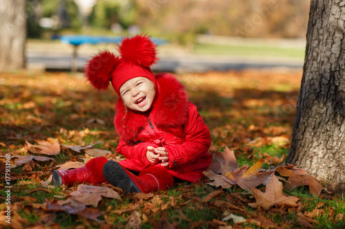 Dolly pin-up toothsome young girl wearing red blushful winter jacket and warm hat with boots fashion stylish clothes posing in autumn spring park weekend happyly smiling sitting on pathway track. © TwinkleStudio