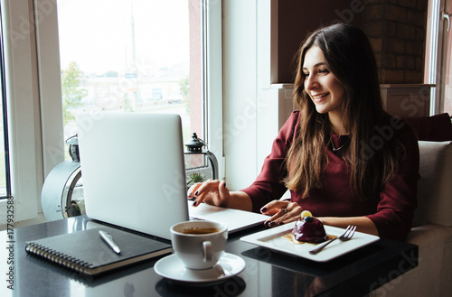 Young attractive woman sitting in a cafe in the morning before her work and planning tasks for the whole day. Beautiful lady talking on the phone and discussing business strategies with her colleague.
