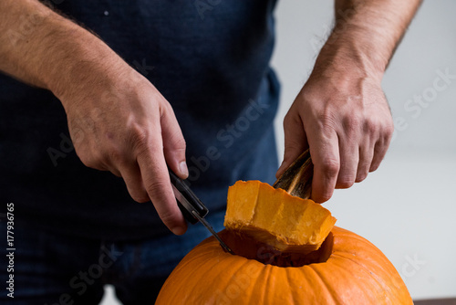 Male hands carving pumpkin