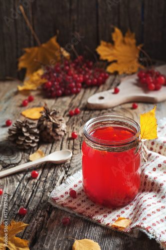 Close up hot Red Drink in glass with cranberry or viburnum berry on wooden table with autumn leaves at village. Food Drink Family Tradition Cooking cuisine concepts. Cozy evening at home holiday
