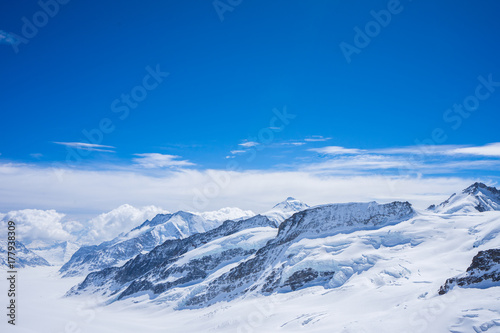 Clear blue sky with the big cloud look like soft cotton candy on the top of the high mountain with snow cover