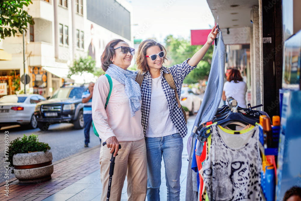An attractive woman with her adult daughter is walking along the street and shopping in street shops