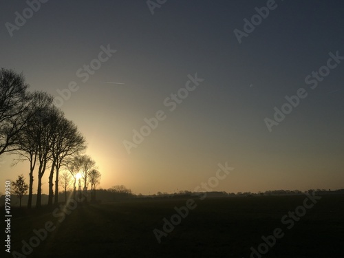Dramatic golden sunrise over a lovely green natural landscape with glowing sunbeams in a blue sky