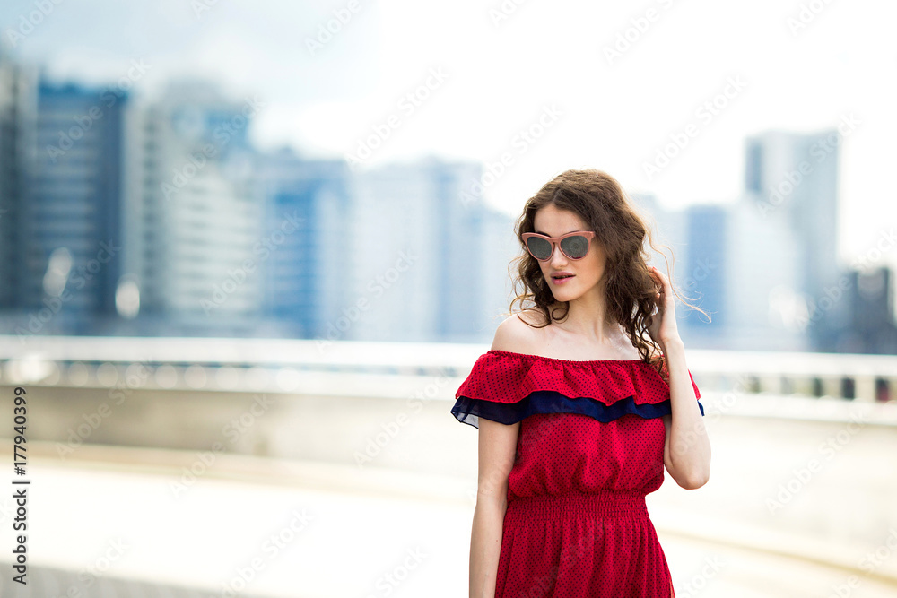 A portrait of a beautiful girl in glasses in a red dress