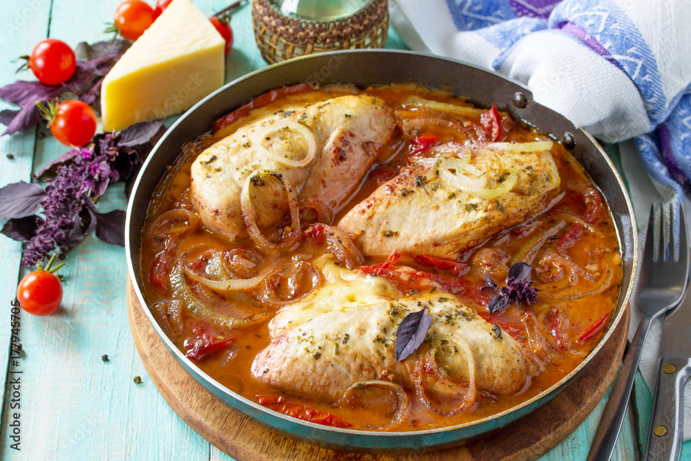 Baked chicken stuffed with tomatoes and cheese in a frying pan on the kitchen table. Baked chicken stuffed with tomatoes and cheese in a frying pan on the kitchen table.