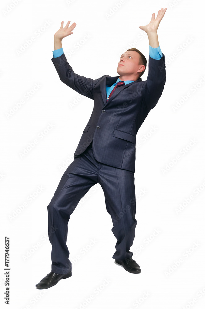 A young business man stands on bent knees and holds his hands above his head as if he is carrying something or holding it, isolated on white background.