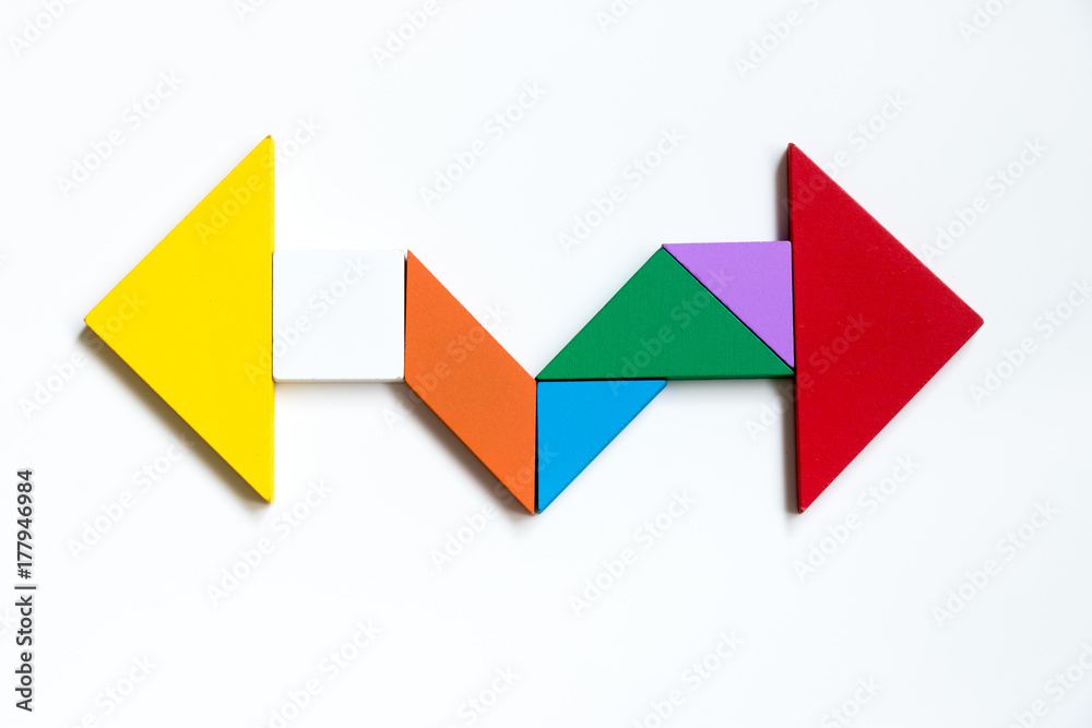 Color wood tangram puzzle on direction arrow shape in the opposite side on white background Color wood tangram puzzle on direction arrow shape in the opposite side on white background