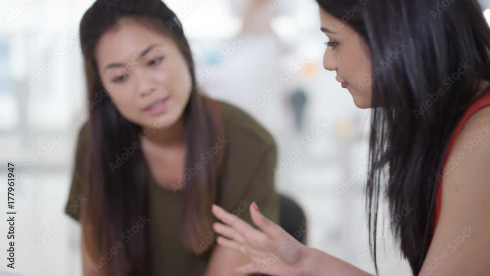 Businesswomen in a meeting looking at photos of a power plant & discussing Businesswomen in a meeting looking at photos of a power plant & discussing