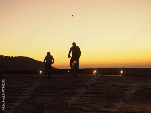 Father and son ridding bicycle in the sunset