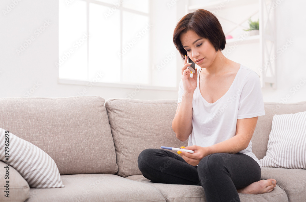 Upset girl holding pregnancy test and making call Upset girl holding pregnancy test and making call