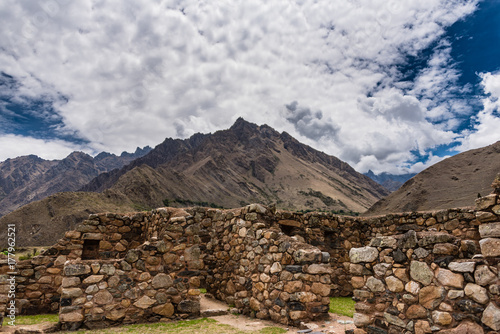 Incan ruins with mountain range backdrop.