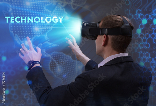Business, Technology, Internet and network concept. Young businessman working in virtual reality glasses sees the inscription: Technology