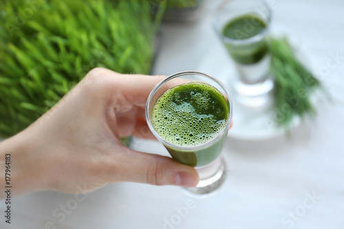 Hand of young man with shot of wheat grass juice