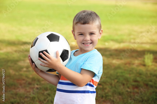Cute little boy holding ball outdoors