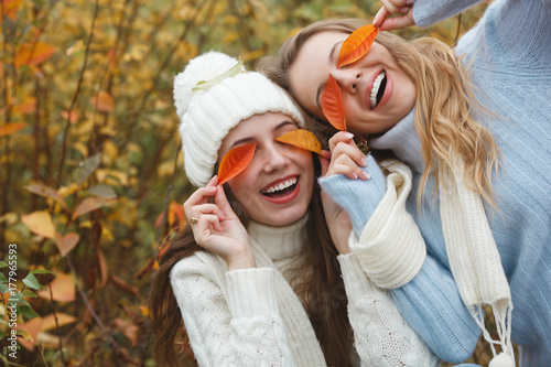 Beautiful girlfriends on the autumn background having fun. Cheerful women in the fall time. Smiling girlfriends outdoors