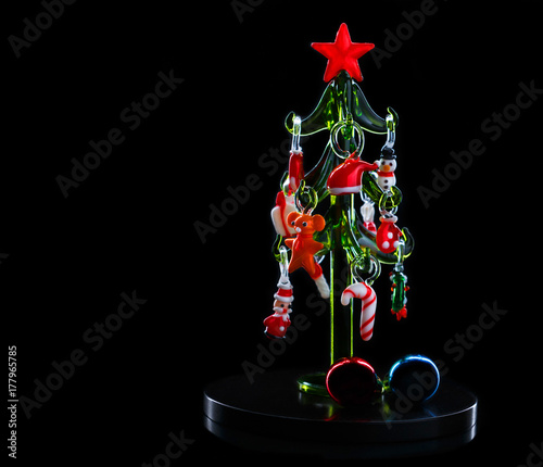 Glass christmas tree with christmas decorations on dark background