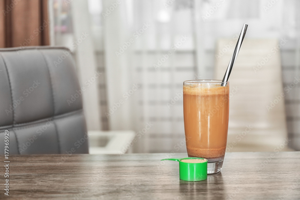 Glass with protein shake and powder on table Glass with protein shake and powder on table