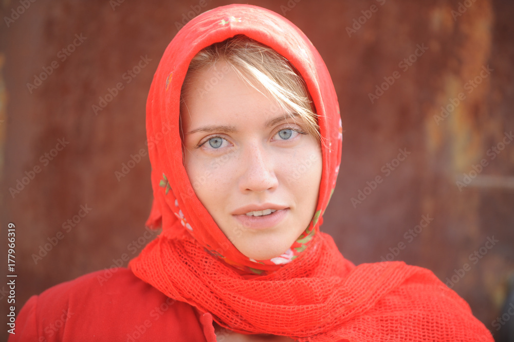 A blonde with blue eyes in a red kerchief is working on the farm. The concept of female beauty and perfection.