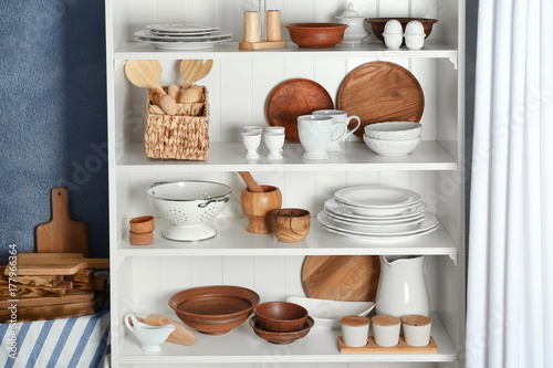 White storage stand with dishware and kitchen utensils indoors