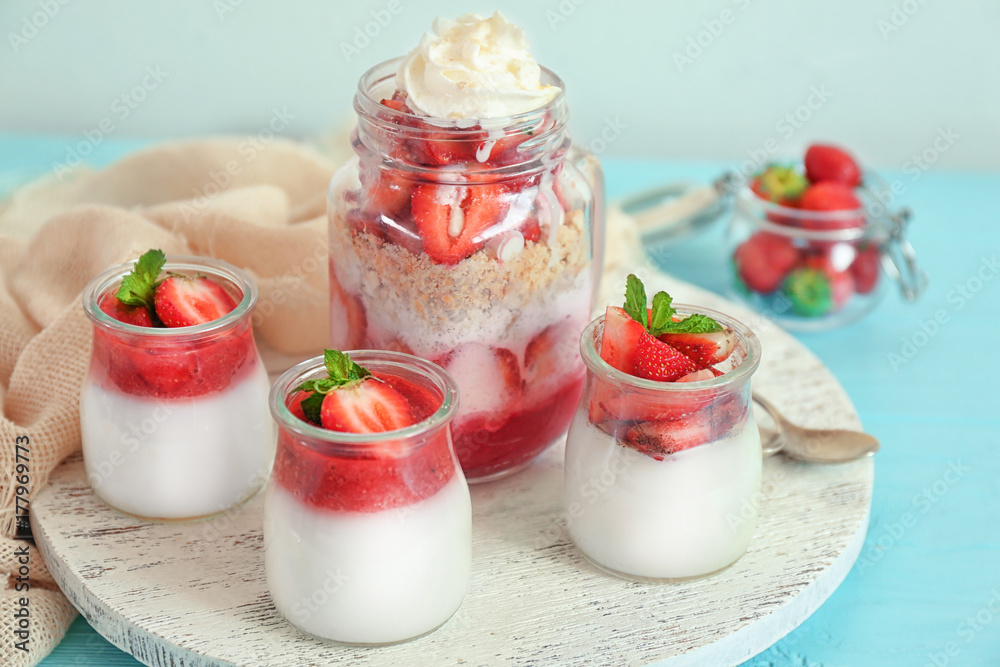 Board with jars of tasty strawberry dessert on table Board with jars of tasty strawberry dessert on table