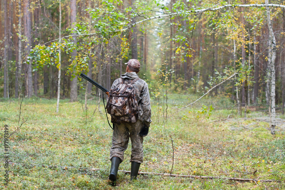 hunter with hunting gun walking in the forest