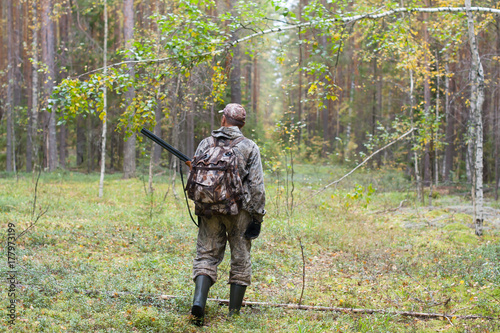 hunter with hunting gun walking in the forest