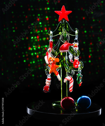 Glass christmas tree with christmas decorations on dark background with blurred lights