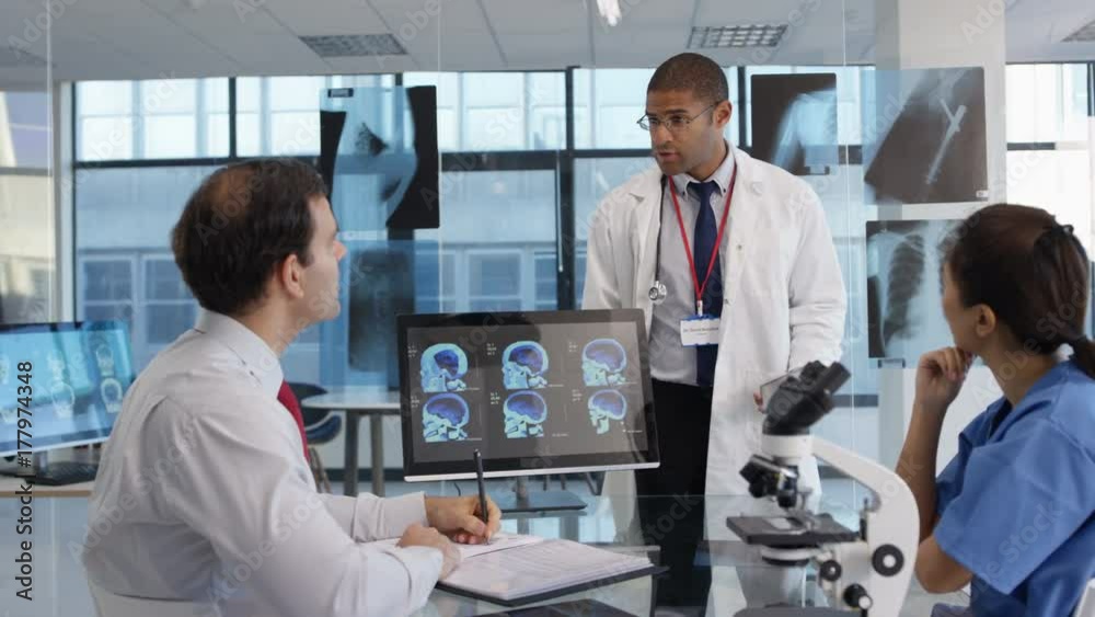 Medical team in a meeting, using technology to look at brain scans & x ...