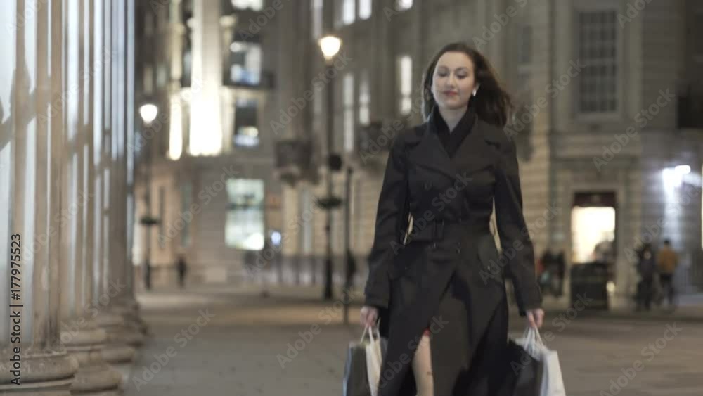 Portrait beautiful smiling girl walking with shopping bags in city at night Portrait beautiful smiling girl walking with shopping bags in city at night