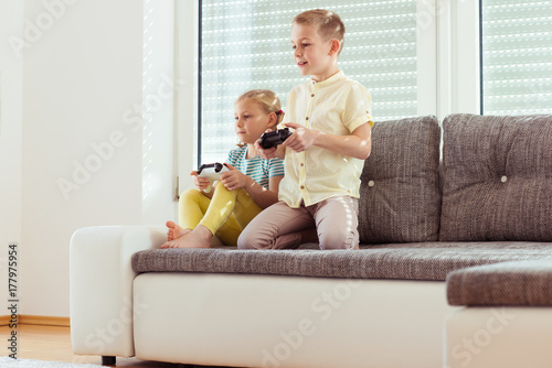 Two happy children playing video games at home