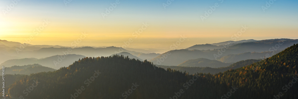 Fototapeta premium Autumn landscape - Black Forest. Panoramic view over the autumnal Black Forest, the Rhine valley and the Vosges (France) in the distance at sunset.