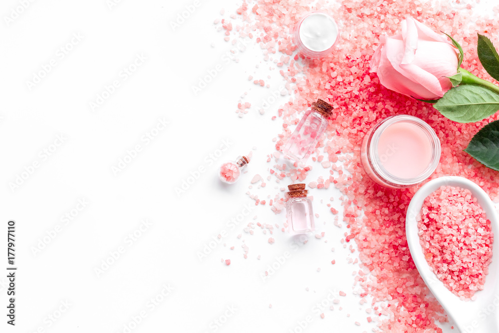 Rose bath salt in spoon near rose petals on white background top view copyspace Rose bath salt in spoon near rose petals on white background top view copyspace