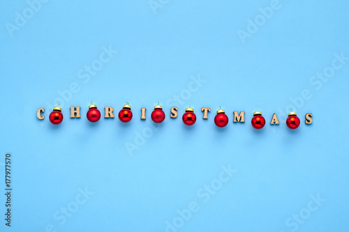 A xmas card. Holiday pattern of inscription Christmas and red balls on a blue background. Winter concept 