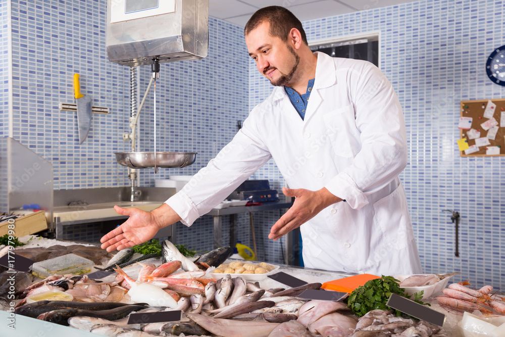 Adult cheerful man standing near fish counter