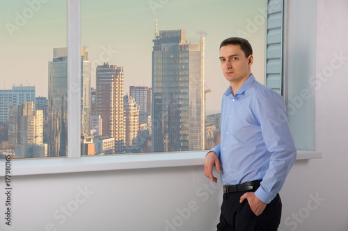 Man experienced managing director dressed in skirt is resting after conference with his staff, while is standing near office window background with copy space for your advertising text message photo