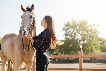 Young woman taking care about horse on a farm run by her grandfather. Soon to become a stallion manager.