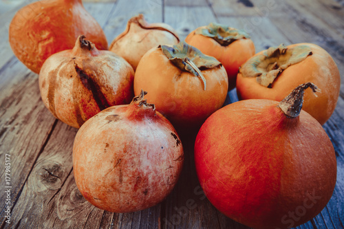 Fresh persimmon , pumpkin and pomegranate fruit on a wooden board