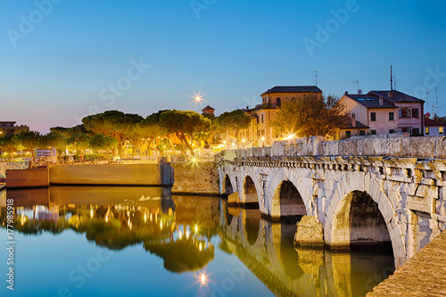 Historical roman Tiberius bridge over Marecchia river during sunset in Rimini, Italy. photo
