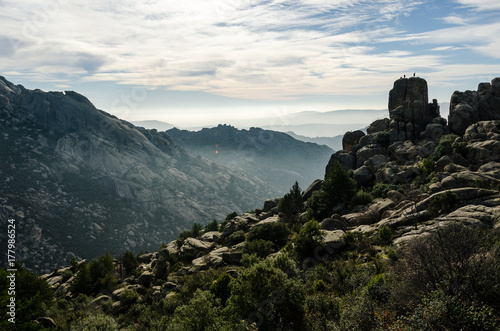 Some climbers at the very top of a rounded rock in La Pedriza Regional Park, Madrid