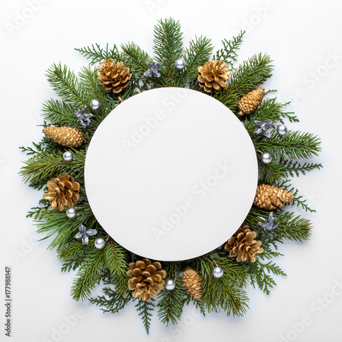 Paper blank, christmas tree branches and golden decorations on white background. Flat lay, top view, copy space.