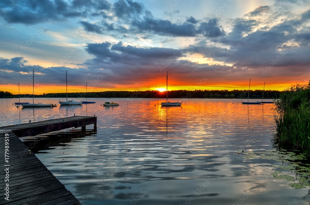 Beautiful summer evening landscape. Wooden pier and boat on the lake at sunset.