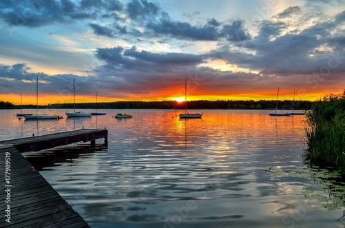 Beautiful summer evening landscape. Wooden pier and boat on the lake at sunset.