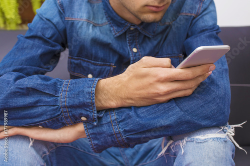 young man sitting on the couch with the mobile phone