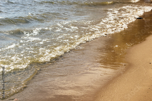 Soft waves on a sandy seashore. Sea beach on a sunny day.