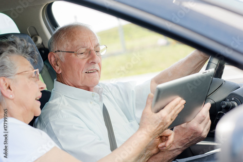 elderly couple in the car with a tablet