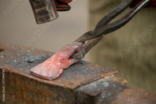 Slika na platnu Master a man forges a axe from a red-hot metal on an anvil