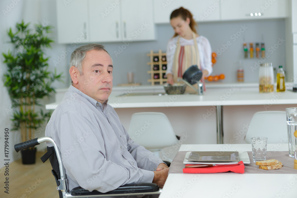 man in wheelchair and young assistant helping