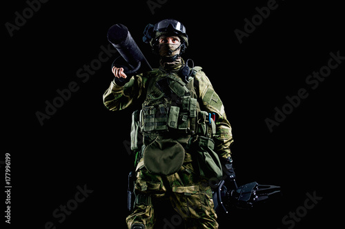 The soldier of the special unit stands in military uniform with a ram on his shoulder and a device for opening the doors. photo