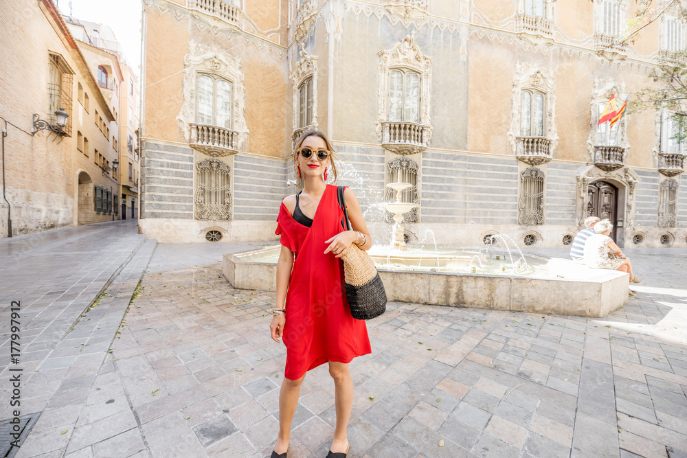 Young woman tourist in red dress walking the street in the old town of Valencia city, Spain